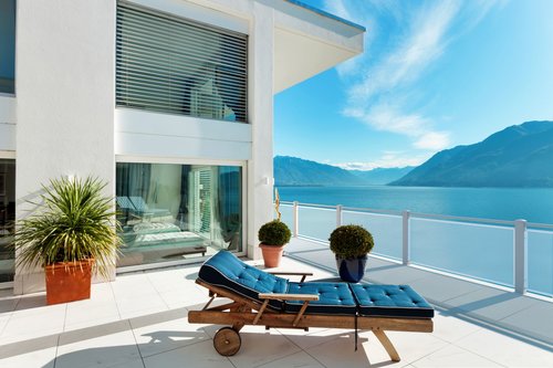 Balkon mit Lochblechfüllung in weiß, mit Handlauf Comfort, Modell Loos, Balkon mit Liege und Pflanzen, Ausblick auf See und Berge